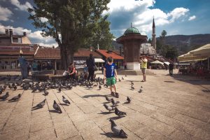 Boy and pigeons against the backdrop of Sebilj, Baščaršija, Sarajevo
