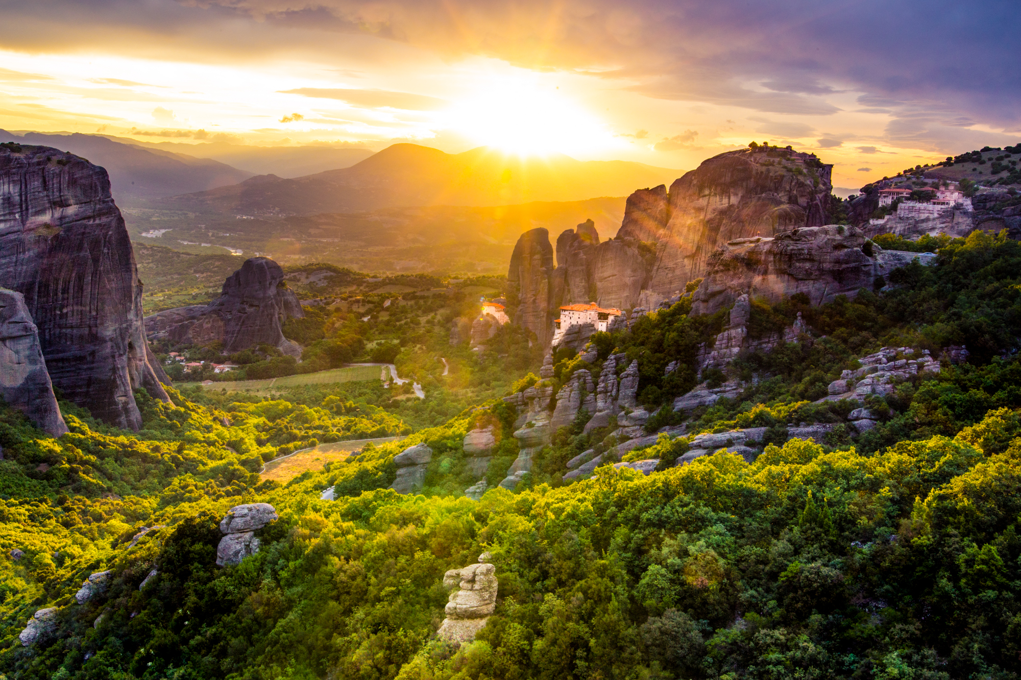Blazing sunset from behind parted storm clouds across the valley in Meteora